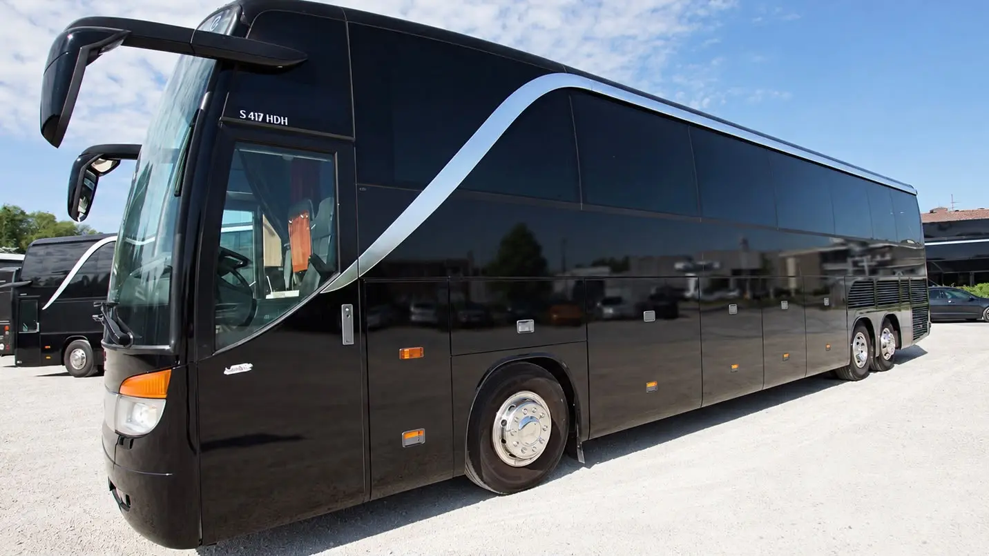 Schwarzer Nightliner Tourbus von Nightliner Service auf einem Parkplatz bei Tageslicht