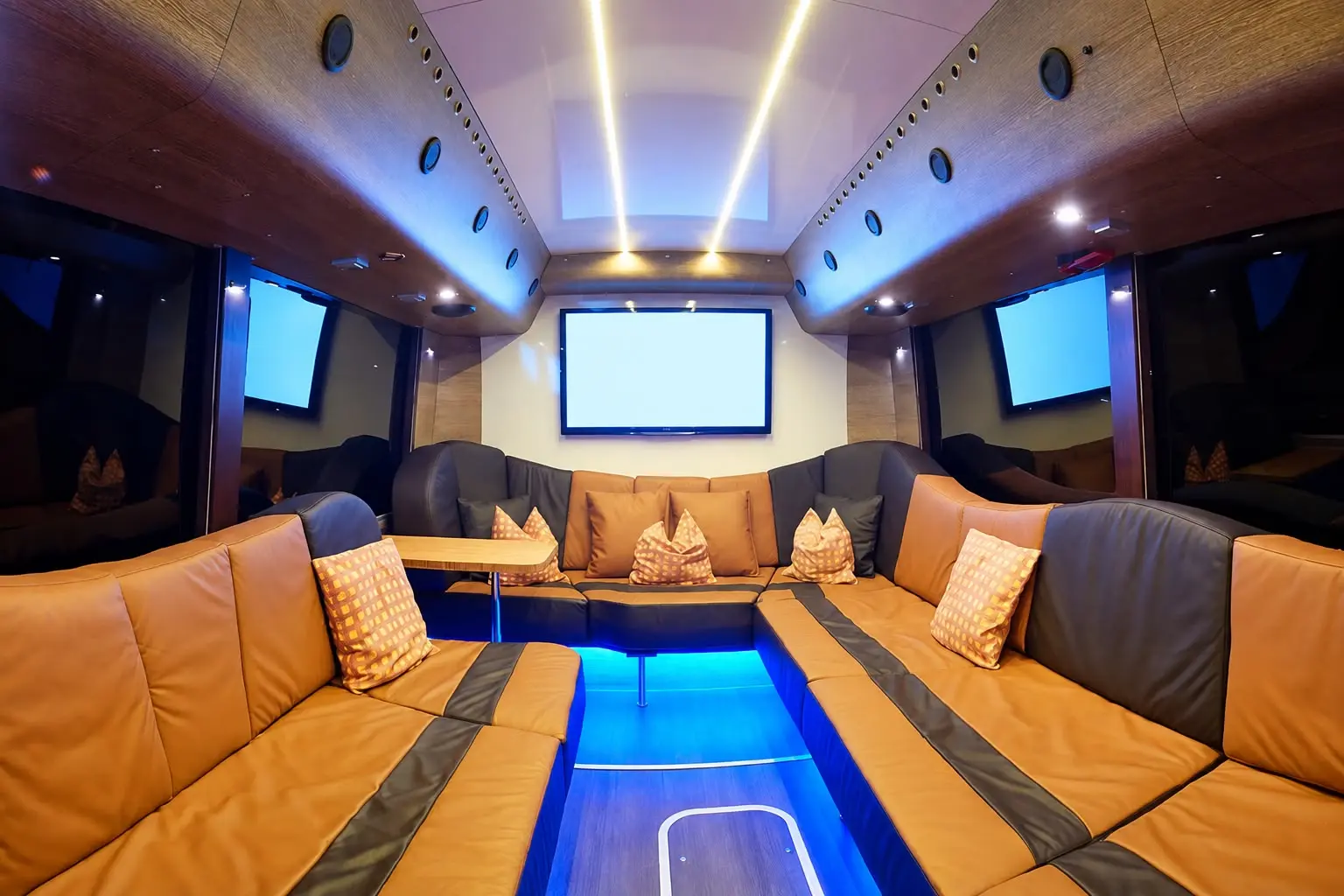 Lounge im Nightliner mit Ledersofa in U-Form und mehreren Bildschirmen